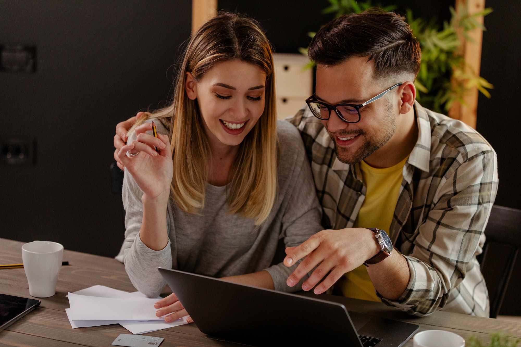 Smiling millennial husband and wife count taxes house expenditures pay bills on internet.
